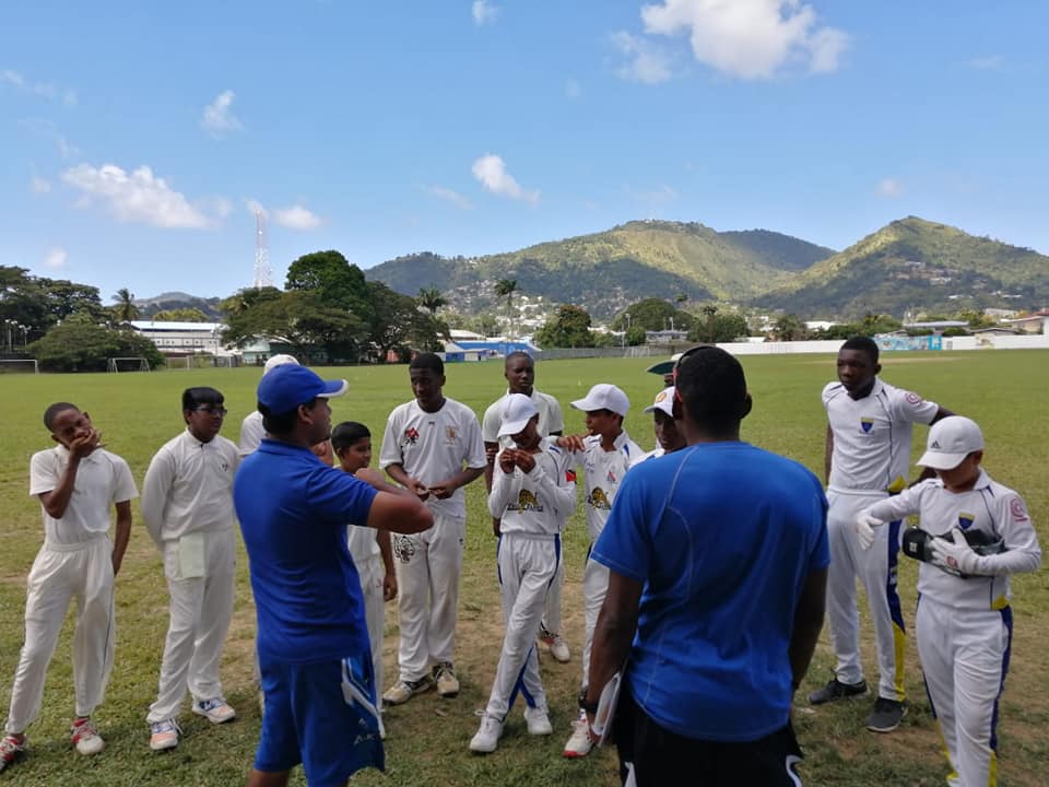 Coach Aaron Kurbanali having a pre-game talk with the team, Manager Dwayne Bourne looks on.